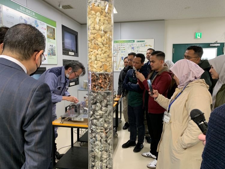 リサイクル工場での部品選別機器について学ぶ参加者